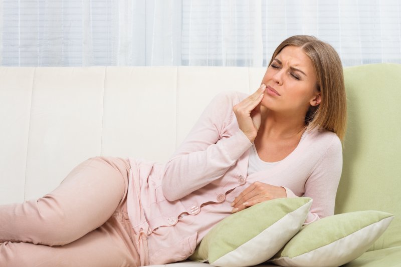 Woman lying on couch at home with toothache