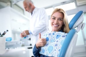 woman giving thumbs up in dental chair before getting dental implants in Reno