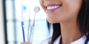 Woman holding teeth cleaning supplies.